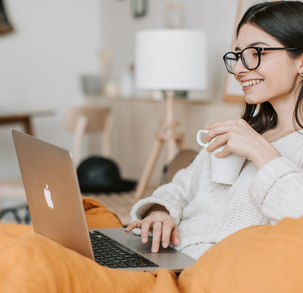 Woman having coffee on a couch and a laptop
